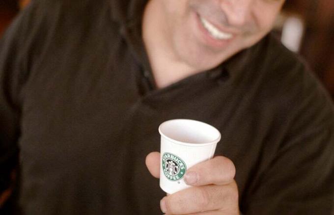 чоловік тримає чашку Starbucks