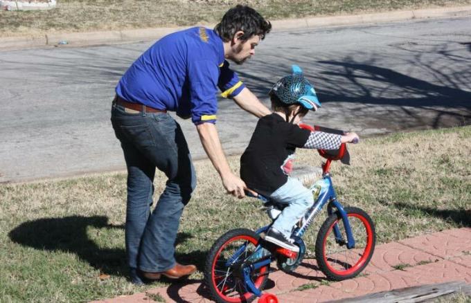 tatăl îl învață pe fiu să meargă cu bicicleta