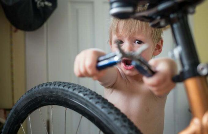 Copil cu unelte multiple care fixează o bicicletă