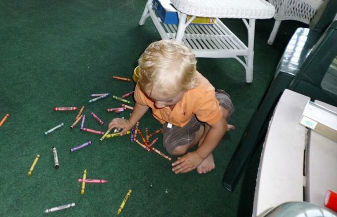 lille barn samler sine farveblyanter op