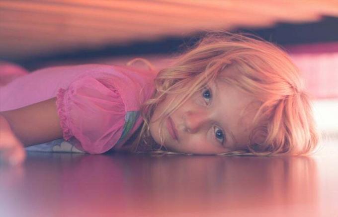 garota se escondendo embaixo da cama