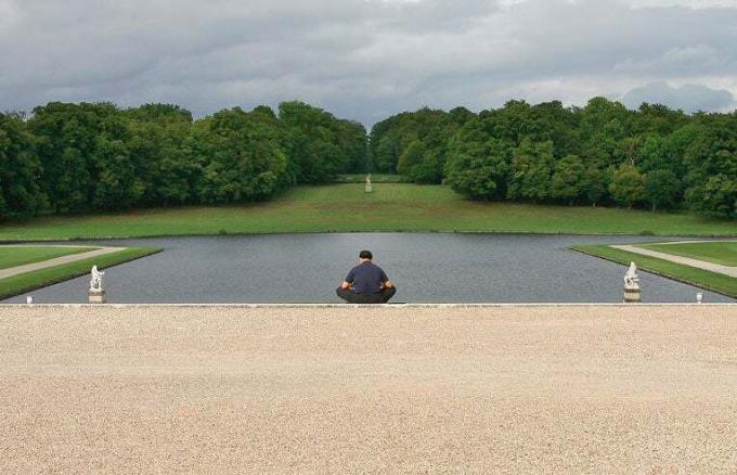 homem meditando perto de um lago
