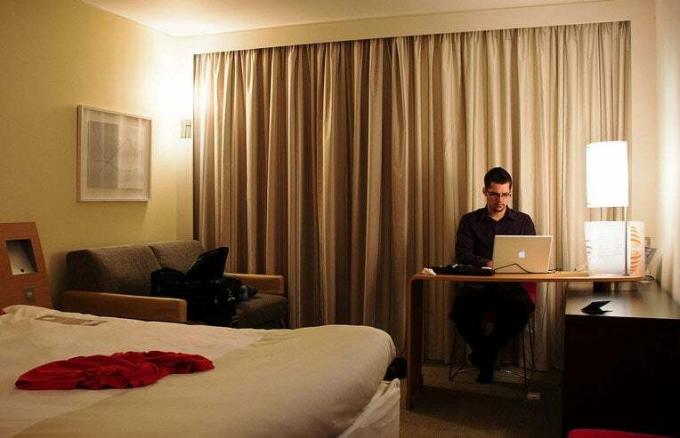 მამაკაცი სასტუმროს ნომერში ლეპტოპს იყენებს