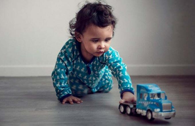 mazulis spēlējas ar rotaļu kravas automašīnu