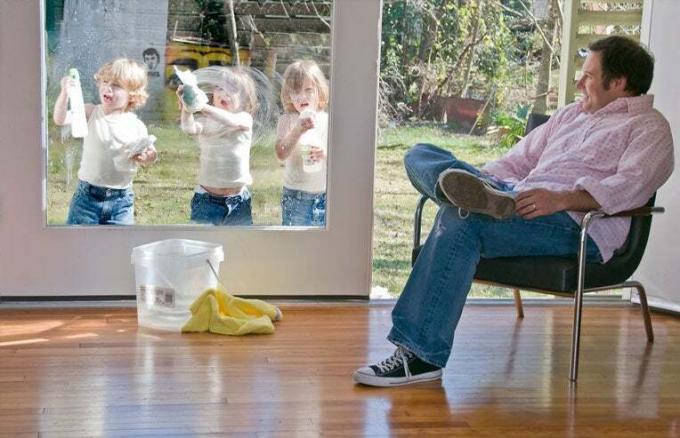 papà che guarda tre gemelli pulire la finestra