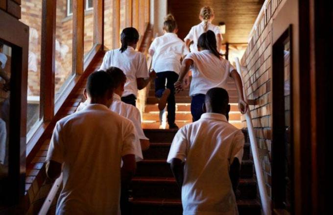 lapset juoksevat portaita ylös koulussa