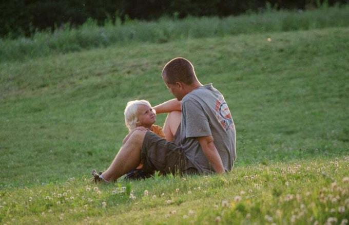 ojciec i syn siedzą na trawie