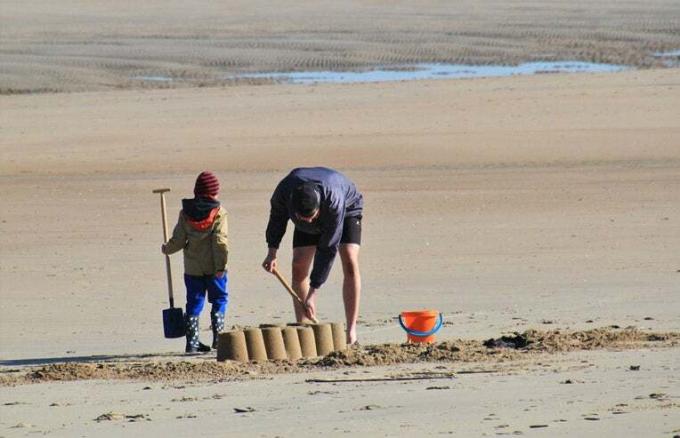 tėvas ir sūnus stato smėlio pilis