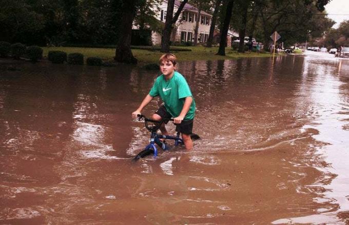 Chłopiec jeździ na rowerze po swojej okolicy, podczas gdy woda nadal podnosi się po huraganie Harvey 30 sierpnia 2017 r. w Houston w Teksasie. Harvey, który wylądował na północ od Bożego Ciała 25 sierpnia, zrzucił prawie 50 cali deszczu w Houston i okolicach. (Zdjęcie: Scott Olson/Getty Images)