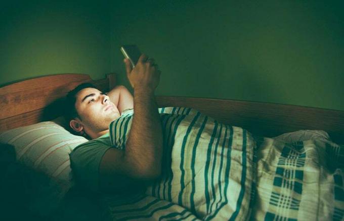ベッドで携帯電話を使用している男