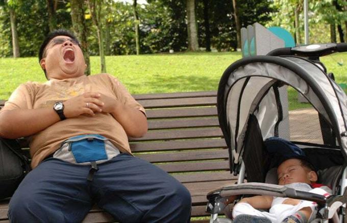 pai sonolento no parque com seu bebê