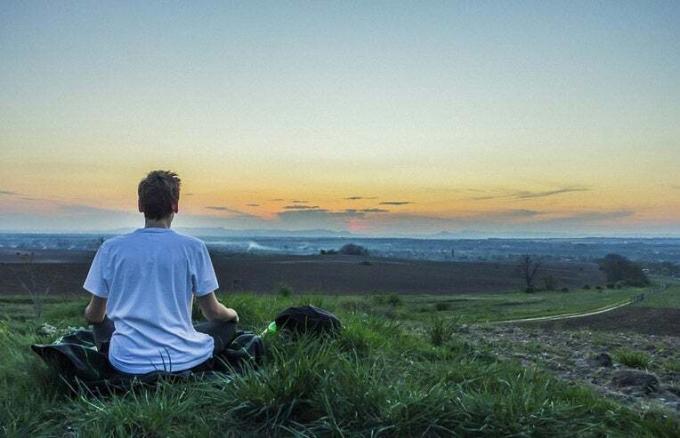 čovjek koji meditira u sumrak