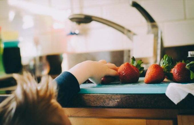 laps sirutab käe maasikate järele